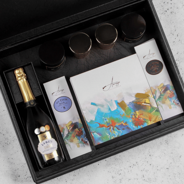 Indulge in Aaraya Chocolates' Luxury Noir Box – a curated selection of signature chocolates, cocoa bars, truffles, scented candles, and non-alcoholic champagne. Immerse yourself in the opulence of fine chocolate craftsmanship, with rich flavors and exquisite aromas.