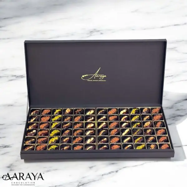 An exquisite assortment of Assorted Luxury Dates by Aaraya Chocolates, showcasing a symphony of premium flavors including Lemon Peel, Pistachio, Orange Peel, Cashew Nut, Salted Hazelnut, Feuilletine Crunch, Walnut, Almond Blanched, and Pistachio Ganache. Each date is a masterpiece of indulgence, promising a sensory journey through the finest gourmet fillings.