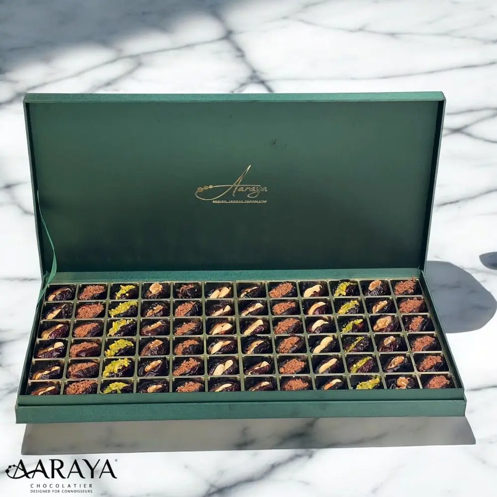 An exquisite assortment of Assorted Luxury Dates by Aaraya Chocolates, showcasing a symphony of premium flavors including Lemon Peel, Pistachio, Orange Peel, Cashew Nut, Salted Hazelnut, Feuilletine Crunch, Walnut, Almond Blanched, and Pistachio Ganache. Each date is a masterpiece of indulgence, promising a sensory journey through the finest gourmet fillings.