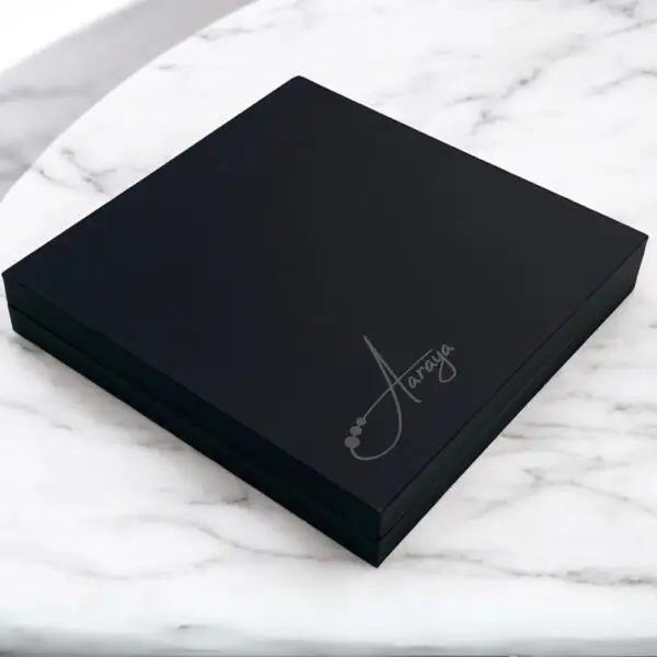 Elegant Noir Indulgence - 70% Dark Chocolate Box displayed on a luxurious white marble table, featuring rich, velvety dark chocolates in sleek black packaging.