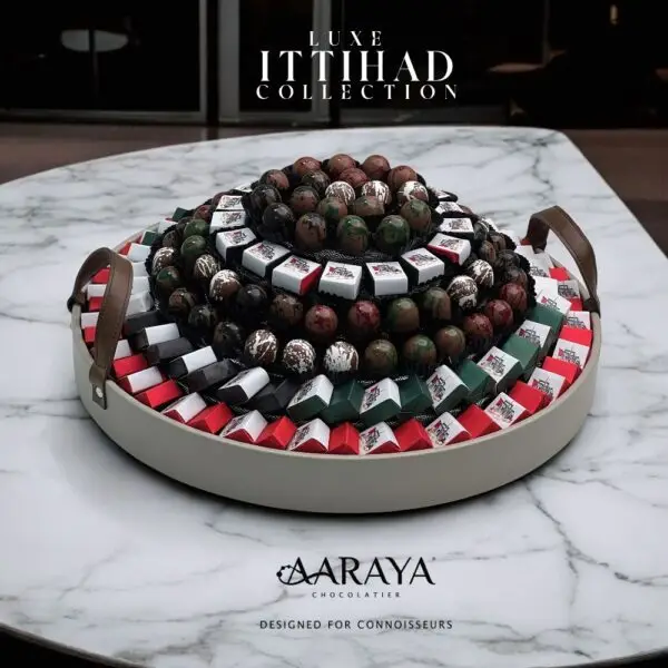 Luxurious NATIONAL DAY LUXE ITIHAAD Collection by AARAYA® Chocolatier for UAE National Day, featuring 180 handcrafted chocolates, including 107 elegantly wrapped chocolates and 73 decadent bon bons, presented in a grand 45 cm display. Total weight of 3.6 kg, with 2.3 kg of artisanal chocolates, celebrating unity, pride, and luxury. Available for AED 1,299