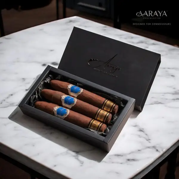 A luxurious handcrafted chocolate cigar by AARAYA®, elegantly designed with intricate details, resting on a premium gift box.